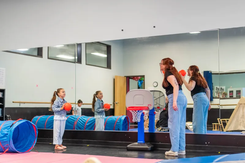 Kids playing ball with teachers in the dance studio movement room