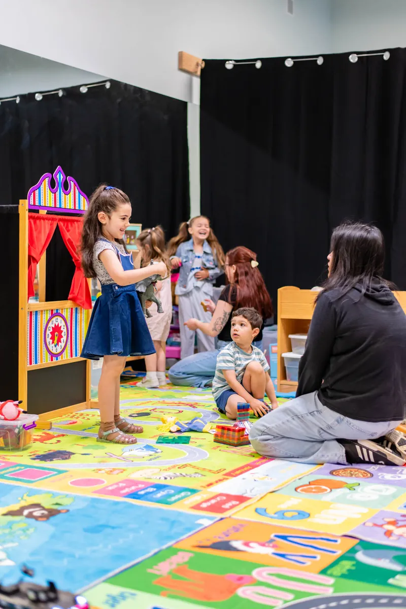 Children and a teacher playing by the puppet theater