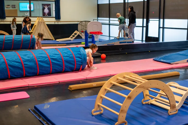Movement room with play tunnels, climbing arch, and soft mats