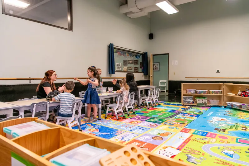 Preschoolers working at classroom tables with their teachers