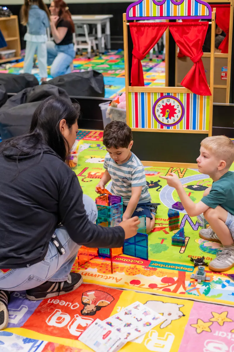 Teacher building with two boys on the classroom play mat